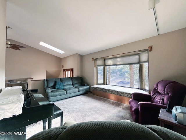 carpeted living area with ceiling fan and vaulted ceiling with skylight