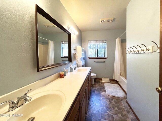 full bath with shower / tub combo, a sink, toilet, and double vanity