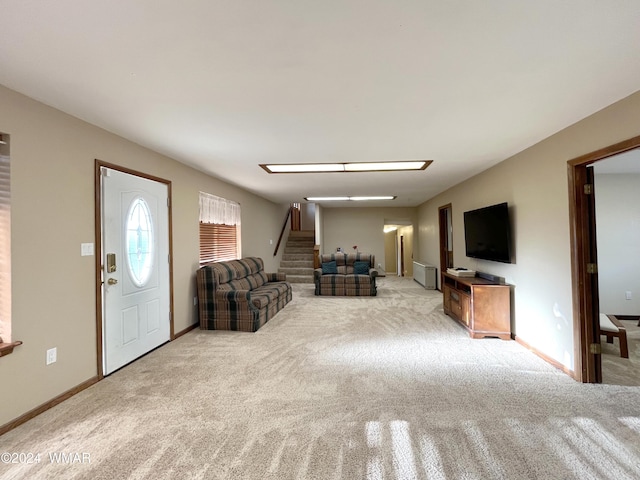 living room with light carpet, stairs, and baseboards