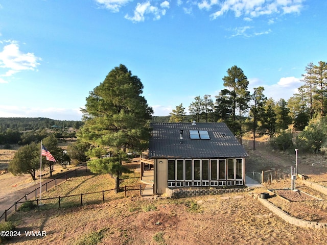 exterior space featuring a sunroom, a garden, metal roof, and fence