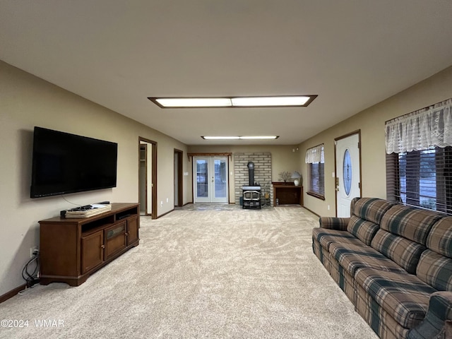 living room with a wood stove, light carpet, and baseboards