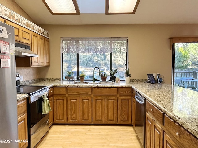 kitchen featuring under cabinet range hood, appliances with stainless steel finishes, brown cabinets, and a sink