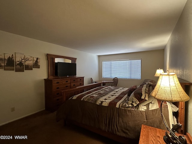 bedroom featuring baseboards and dark carpet