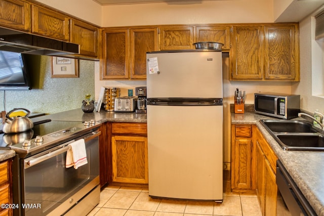 kitchen with appliances with stainless steel finishes, brown cabinetry, and a sink