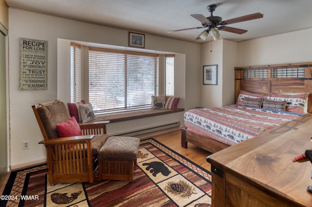 bedroom featuring a baseboard radiator, a textured ceiling, and wood finished floors