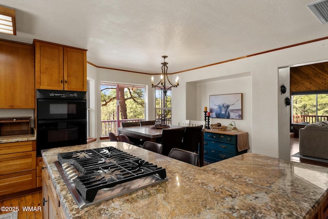746 Jacks Wild Rd, Show Low, AZ 85901 - kitchen with crown molding, an inviting chandelier, stainless steel gas cooktop, dobule oven black, and brown cabinetry