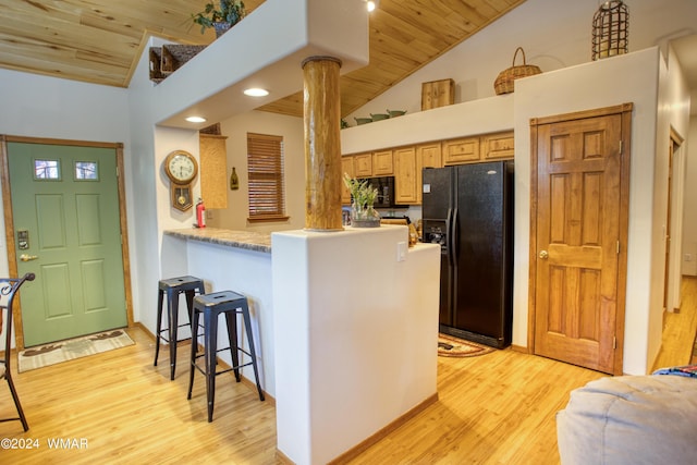 kitchen with wooden ceiling, ornate columns, light wood-type flooring, black appliances, and a kitchen bar