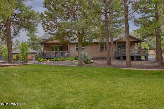 back of house featuring a yard, brick siding, and a wooden deck