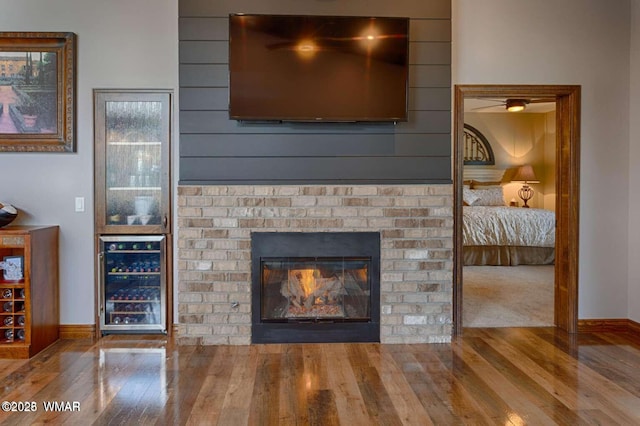 details with a brick fireplace, beverage cooler, baseboards, and wood finished floors