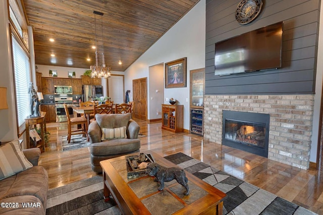 living area featuring high vaulted ceiling, wooden ceiling, beverage cooler, a fireplace, and wood finished floors