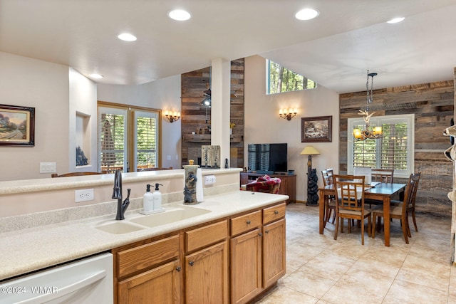 kitchen with white dishwasher, a sink, open floor plan, light countertops, and decorative light fixtures