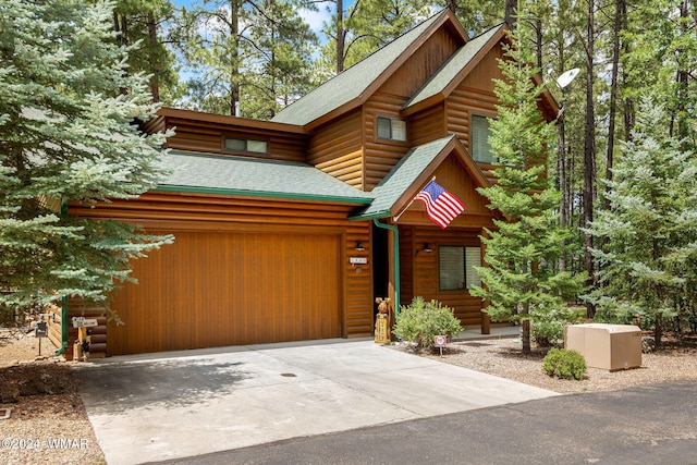 view of front of property featuring driveway, log veneer siding, and roof with shingles