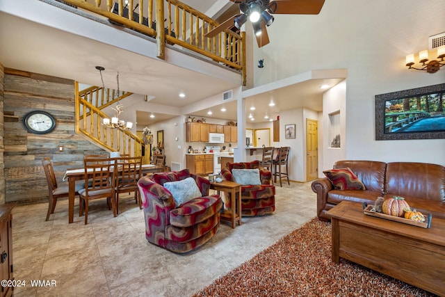 living area with ceiling fan with notable chandelier, visible vents, a towering ceiling, and stairs