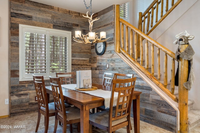 dining area featuring a notable chandelier, wooden walls, and stairs