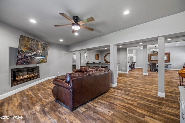 living area featuring baseboards, a glass covered fireplace, dark wood-style floors, ceiling fan, and recessed lighting