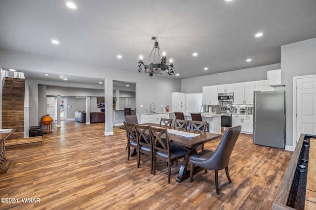 dining area featuring light wood-type flooring, baseboards, a notable chandelier, and recessed lighting