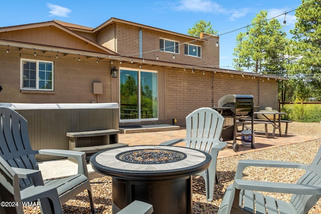 rear view of property with brick siding, a patio, and a fire pit