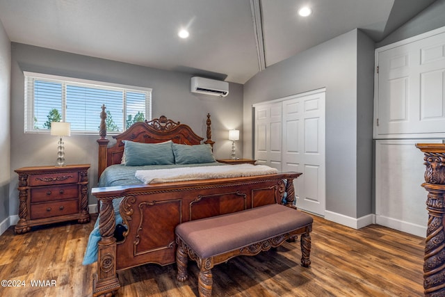 bedroom featuring lofted ceiling, a closet, dark wood-type flooring, a wall mounted air conditioner, and baseboards