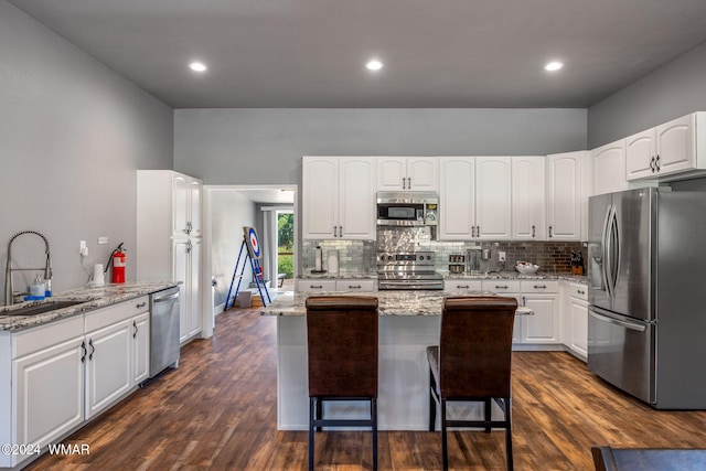 kitchen featuring stainless steel appliances, light stone counters, a sink, and white cabinetry