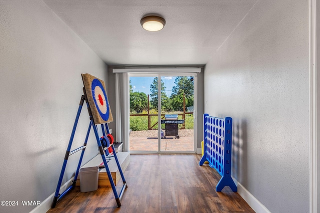 workout room with a textured ceiling, baseboards, dark wood-type flooring, and a textured wall