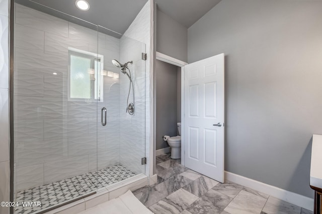 bathroom featuring marble finish floor, toilet, a shower stall, and baseboards