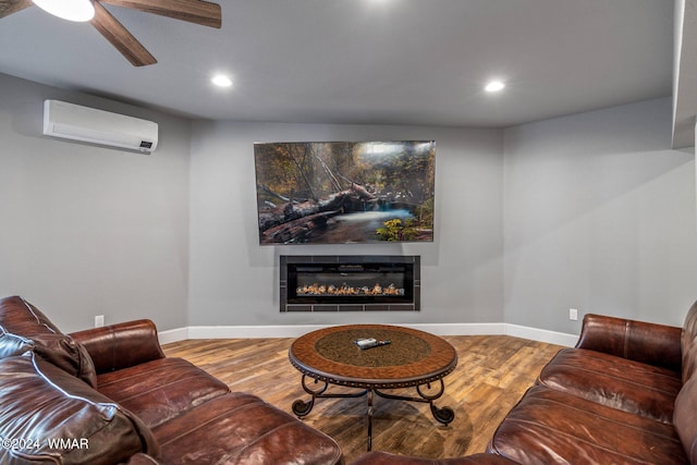 living room with a glass covered fireplace, a wall mounted air conditioner, wood finished floors, and baseboards