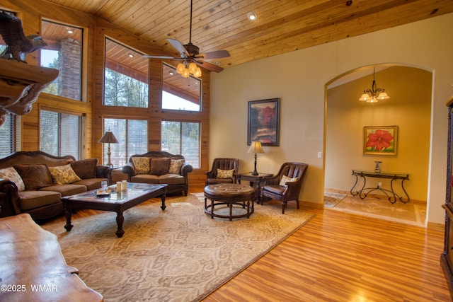 living room with light wood finished floors, high vaulted ceiling, arched walkways, wood ceiling, and ceiling fan with notable chandelier