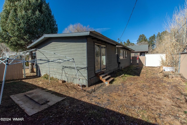 view of home's exterior featuring entry steps, fence, and a gate