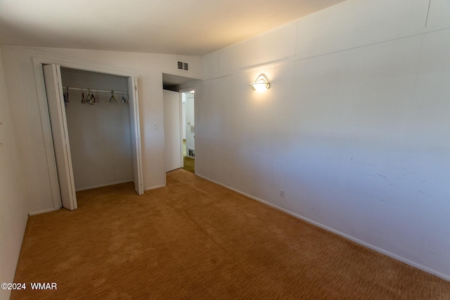 unfurnished bedroom with a closet, visible vents, vaulted ceiling, and light carpet