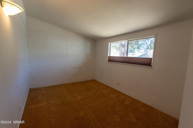 empty room with vaulted ceiling and carpet flooring