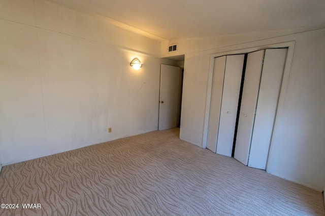 interior space featuring lofted ceiling, a closet, visible vents, and light carpet