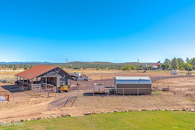 exterior space featuring a rural view, a mountain view, and an outbuilding