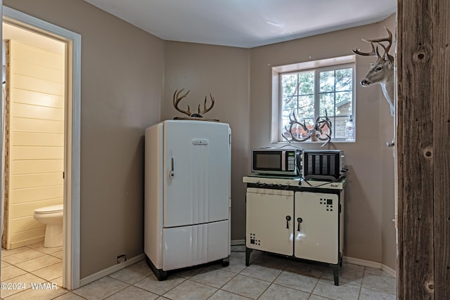 interior space featuring freestanding refrigerator, stainless steel microwave, and baseboards