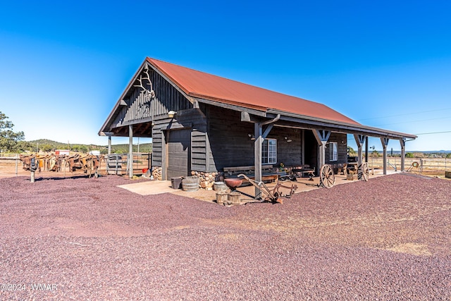 view of front of house with a garage, metal roof, an outdoor structure, and an exterior structure