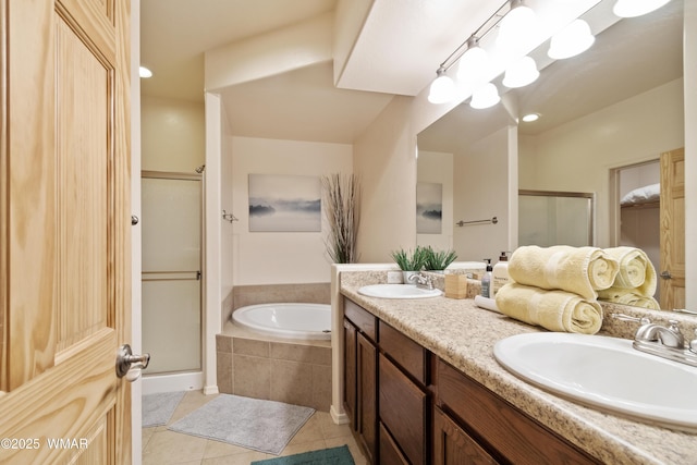 bathroom featuring a bath, a stall shower, a sink, and tile patterned floors