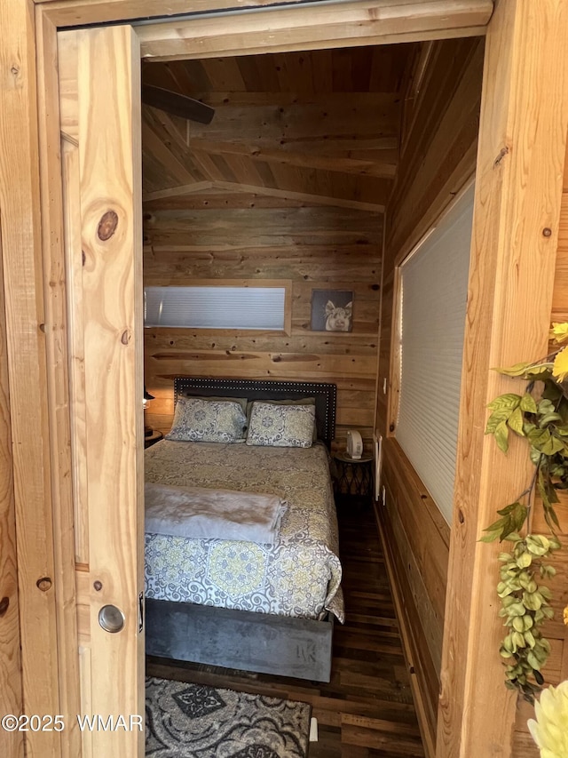 bedroom with lofted ceiling with beams, wood walls, wood finished floors, and wood ceiling