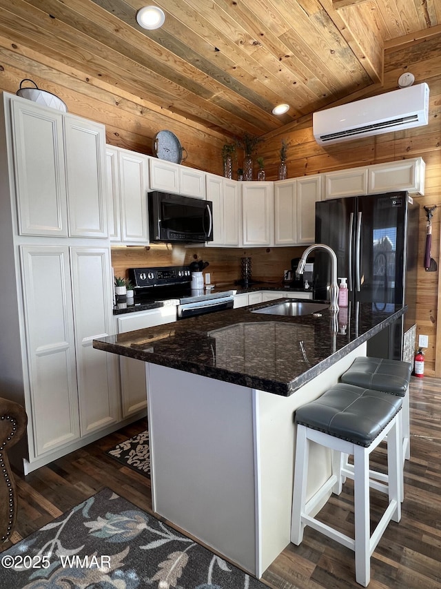 kitchen with lofted ceiling, a wall mounted AC, a sink, wood walls, and black appliances