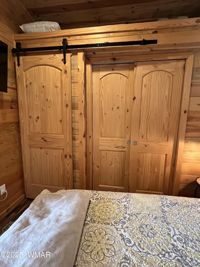 bedroom with wood walls and a barn door