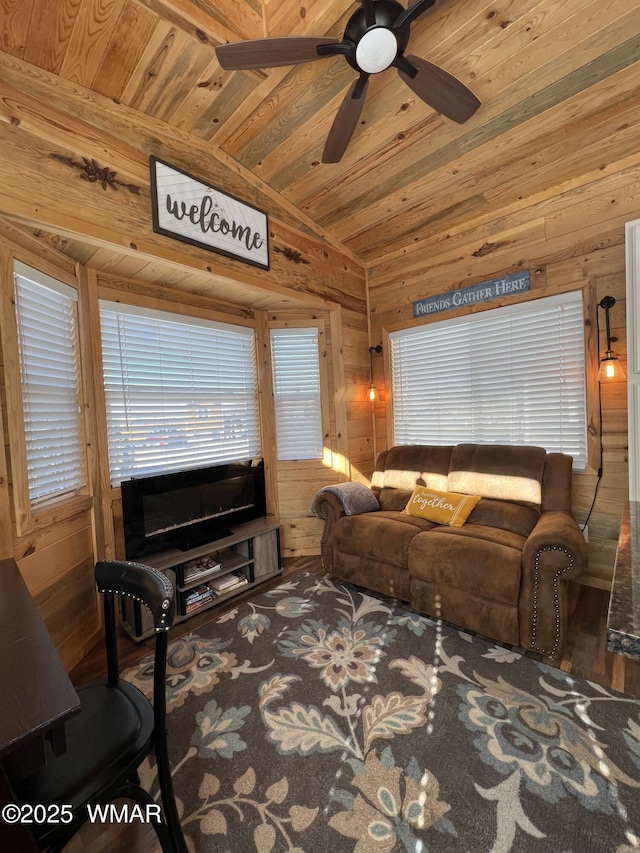 living area with vaulted ceiling, wooden ceiling, and wood walls