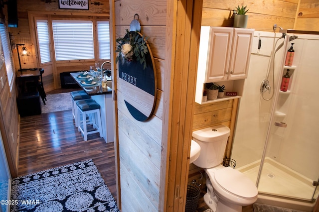 full bath with toilet, a shower stall, and wood finished floors