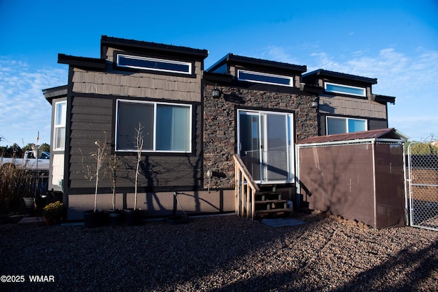 back of property with entry steps and stone siding