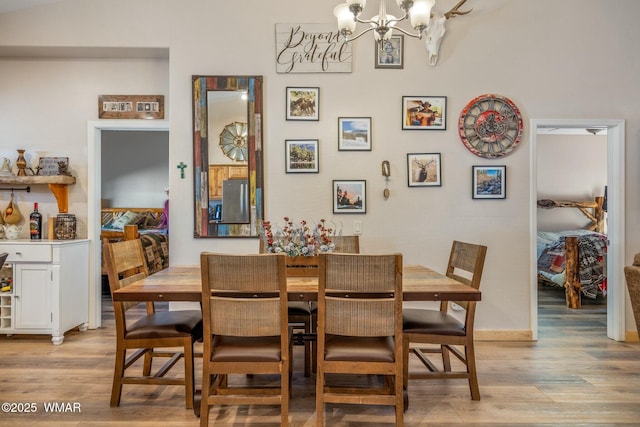 dining area with baseboards, light wood-style flooring, and an inviting chandelier