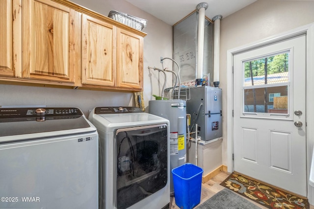clothes washing area featuring light wood-style floors, washing machine and dryer, electric water heater, and cabinet space