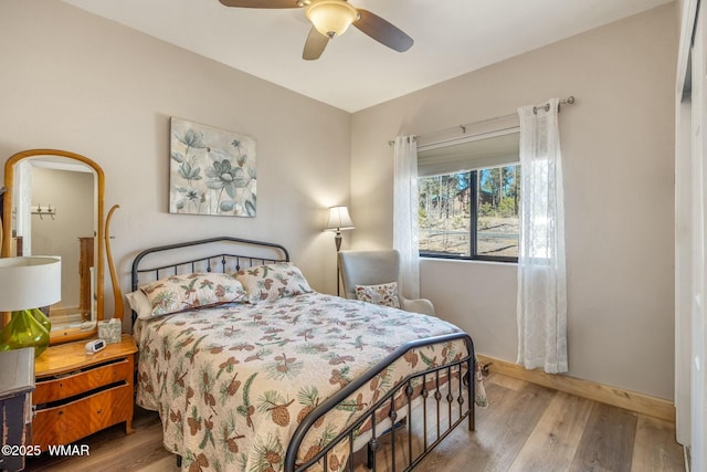 bedroom featuring a ceiling fan, baseboards, and wood finished floors