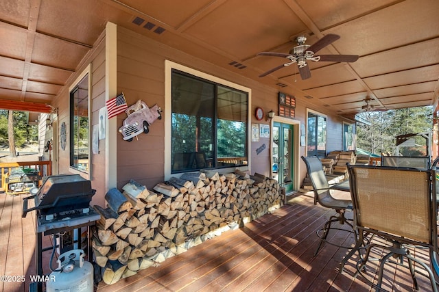 wooden deck featuring visible vents, grilling area, a ceiling fan, and outdoor dining space
