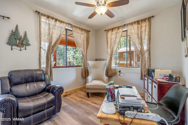 living area with visible vents, wood finished floors, a ceiling fan, and baseboards