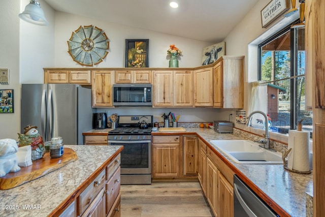 kitchen featuring lofted ceiling, recessed lighting, a sink, appliances with stainless steel finishes, and light wood finished floors