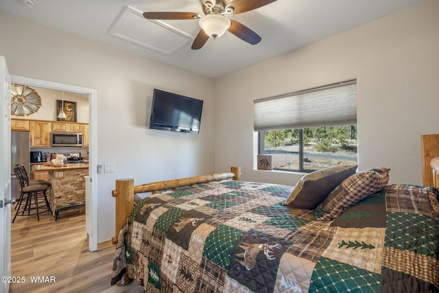 bedroom with light wood-type flooring, attic access, and a ceiling fan