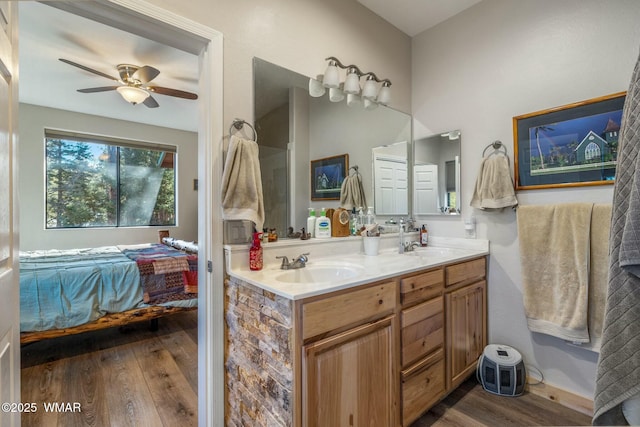 bathroom with double vanity, ensuite bath, a sink, and wood finished floors