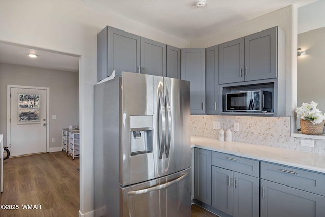 kitchen with dark wood-style floors, stainless steel refrigerator with ice dispenser, gray cabinets, decorative backsplash, and black microwave